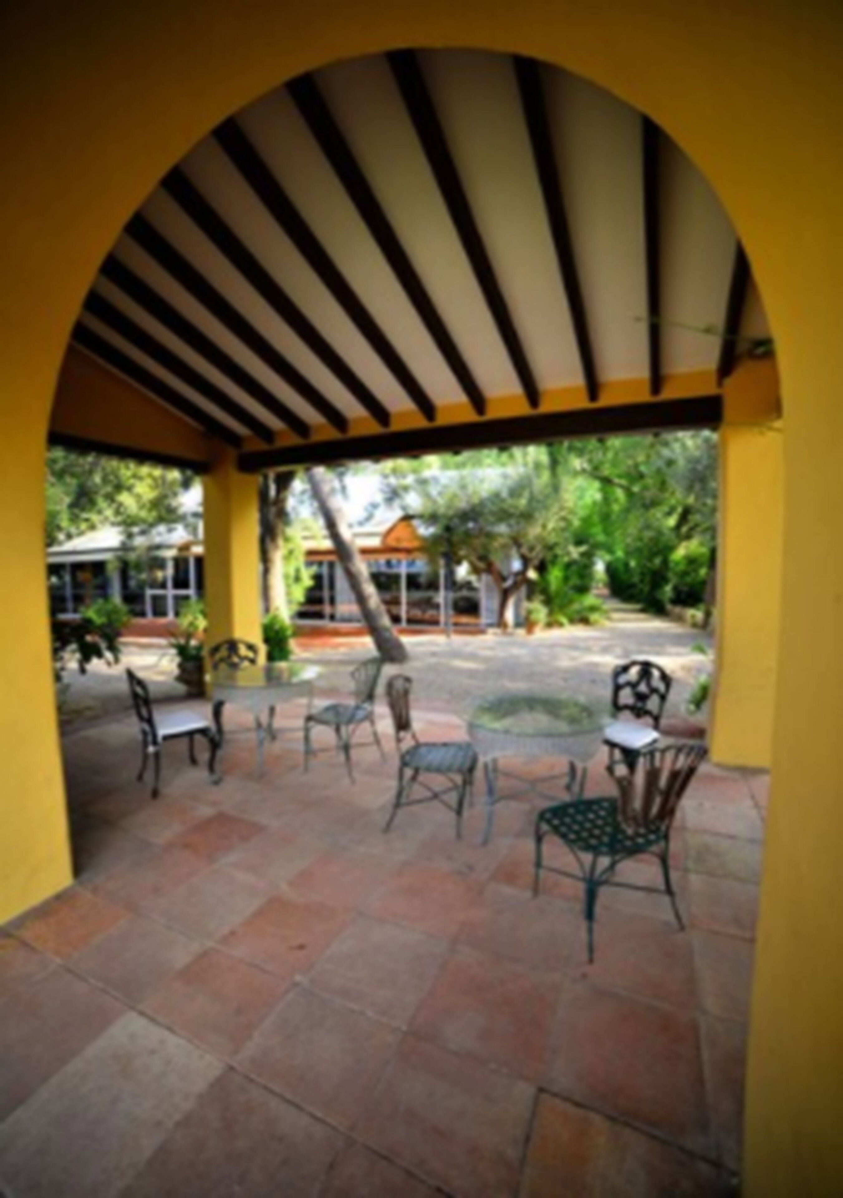A covered patio area with tiled flooring and metal chairs.