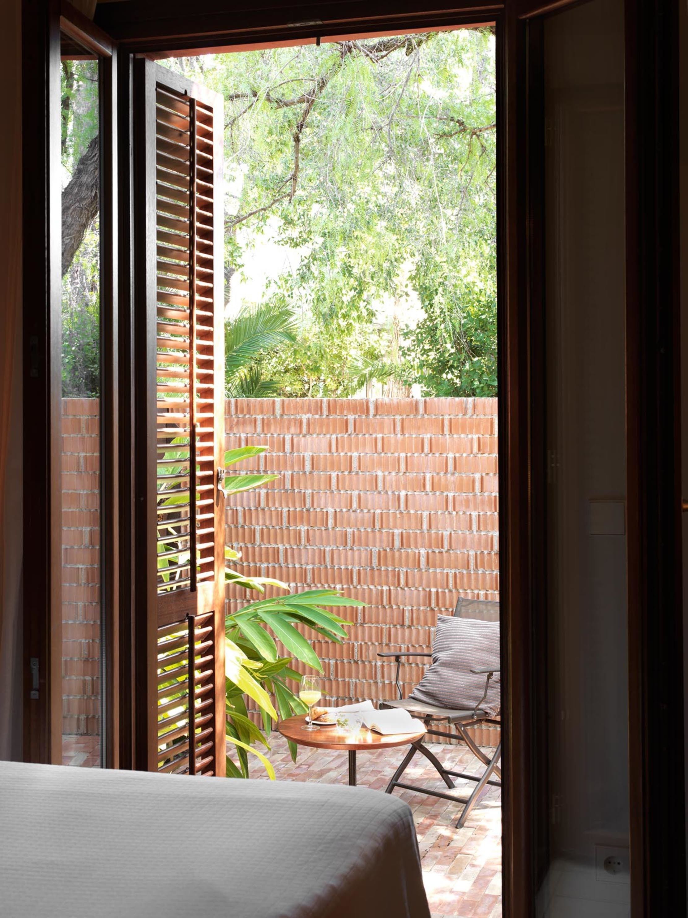 A room with a bed, a small table with a glass, and a chair.