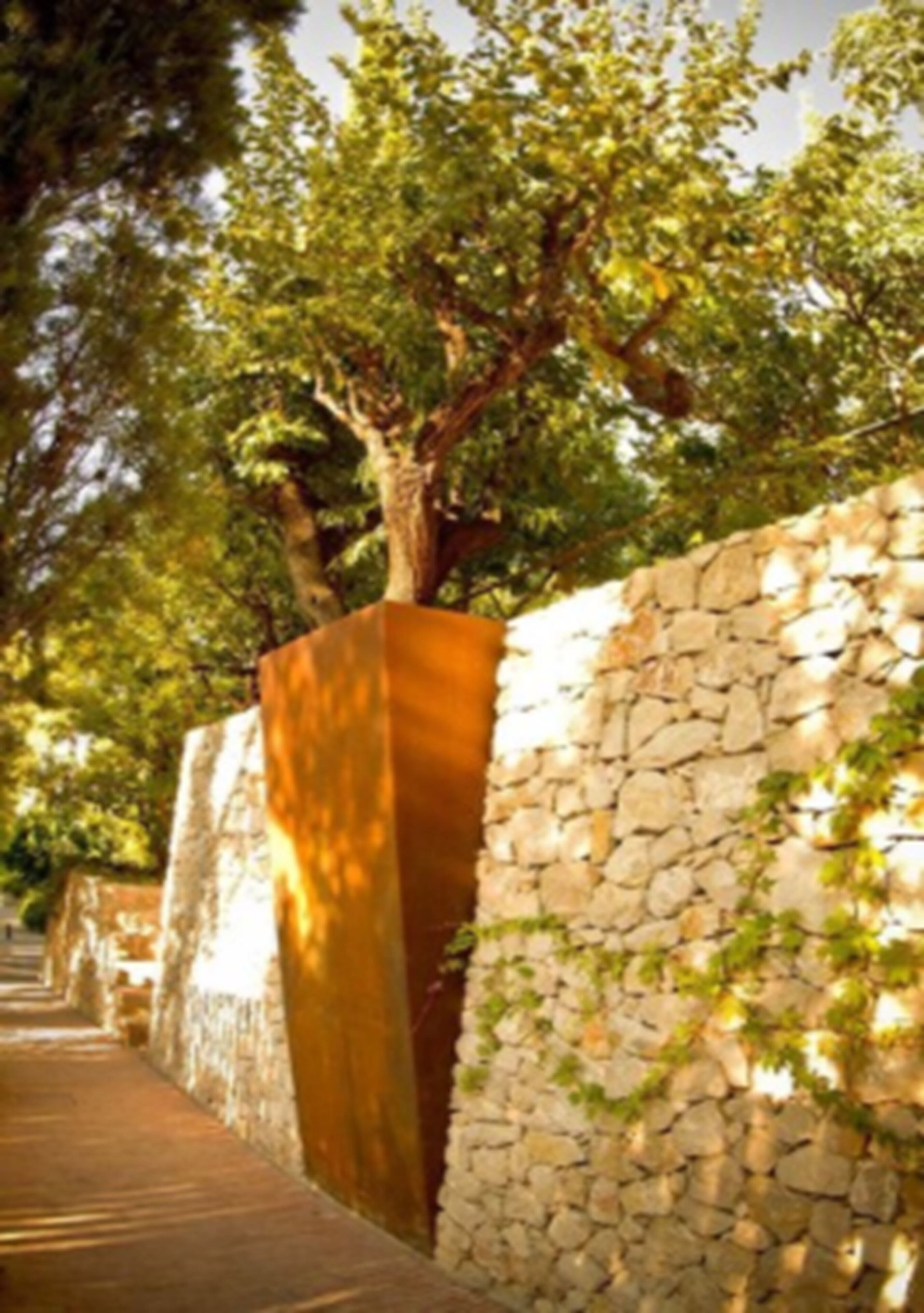 Un muro de piedra con una estructura de madera, rodeado de árboles.