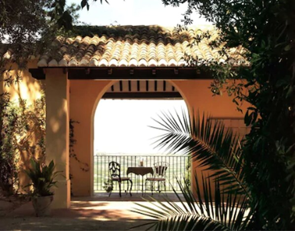 Relax in a shaded patio area surrounded by lush greenery and furnished with a table and two chairs.