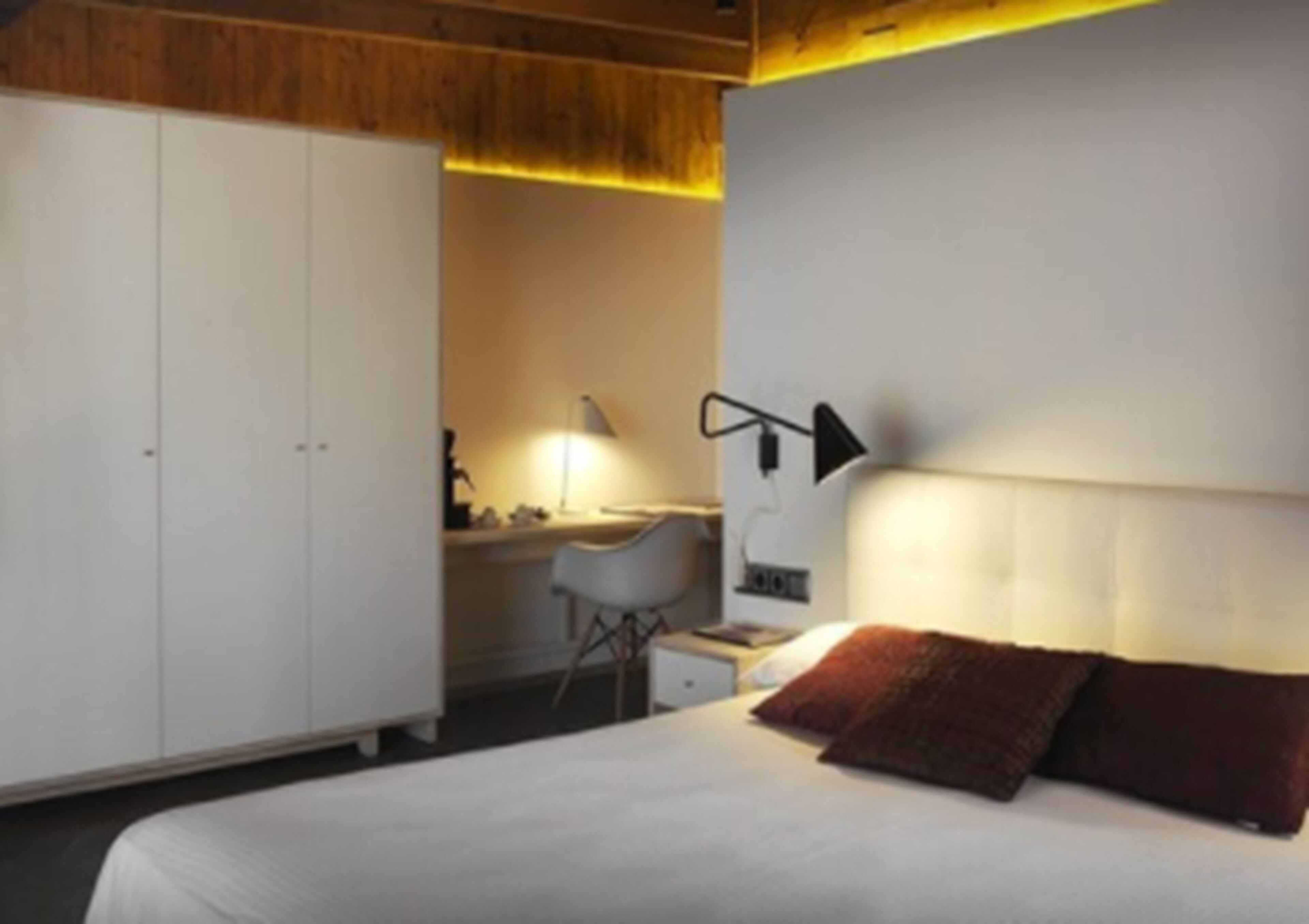 Un dormitorio con cama, escritorio y armario.