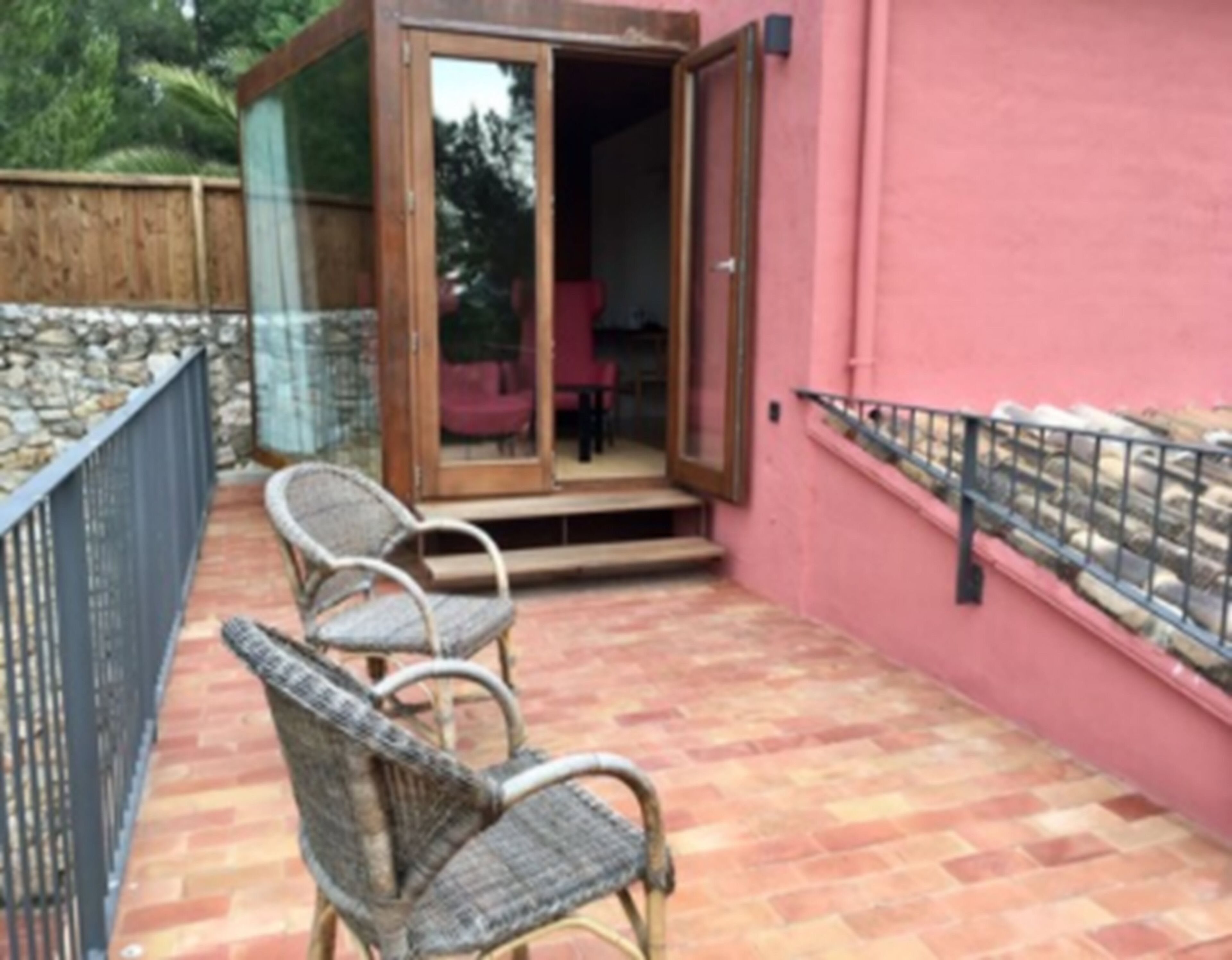 A patio with wicker chairs and a glass door leading to an interior space.