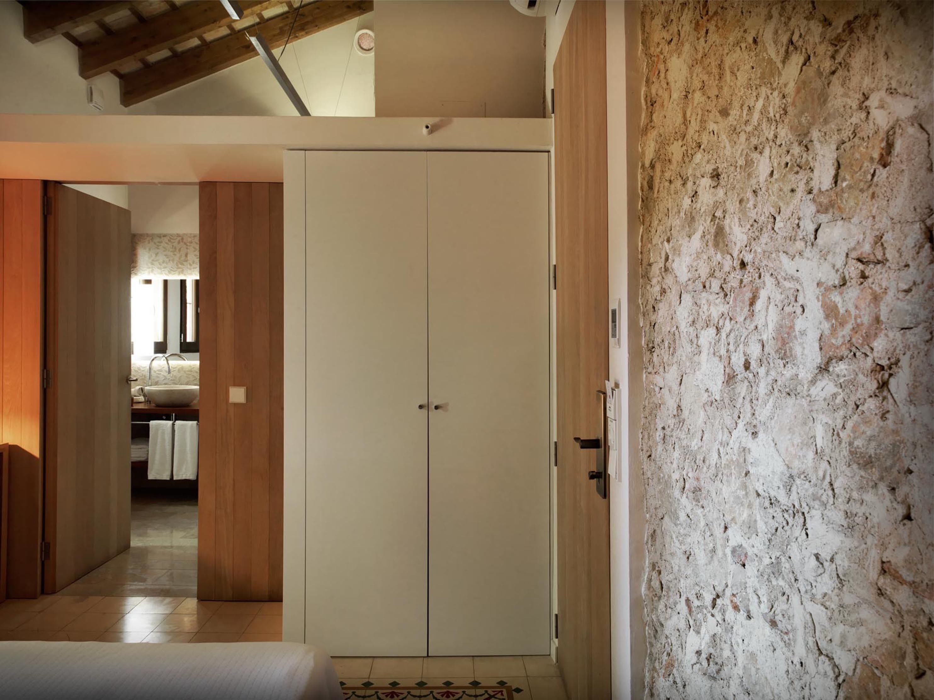 A room with a wooden wardrobe, a white door, and a textured wall.