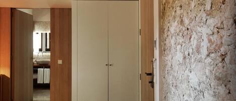 A room with a wooden wardrobe, a white door, and a textured wall.
