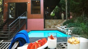 A poolside setting with a dining table, a plate of sliced strawberries, a glass of milk, and a bowl of cereal. - Mont-Sant Hotel (Xàtiva)