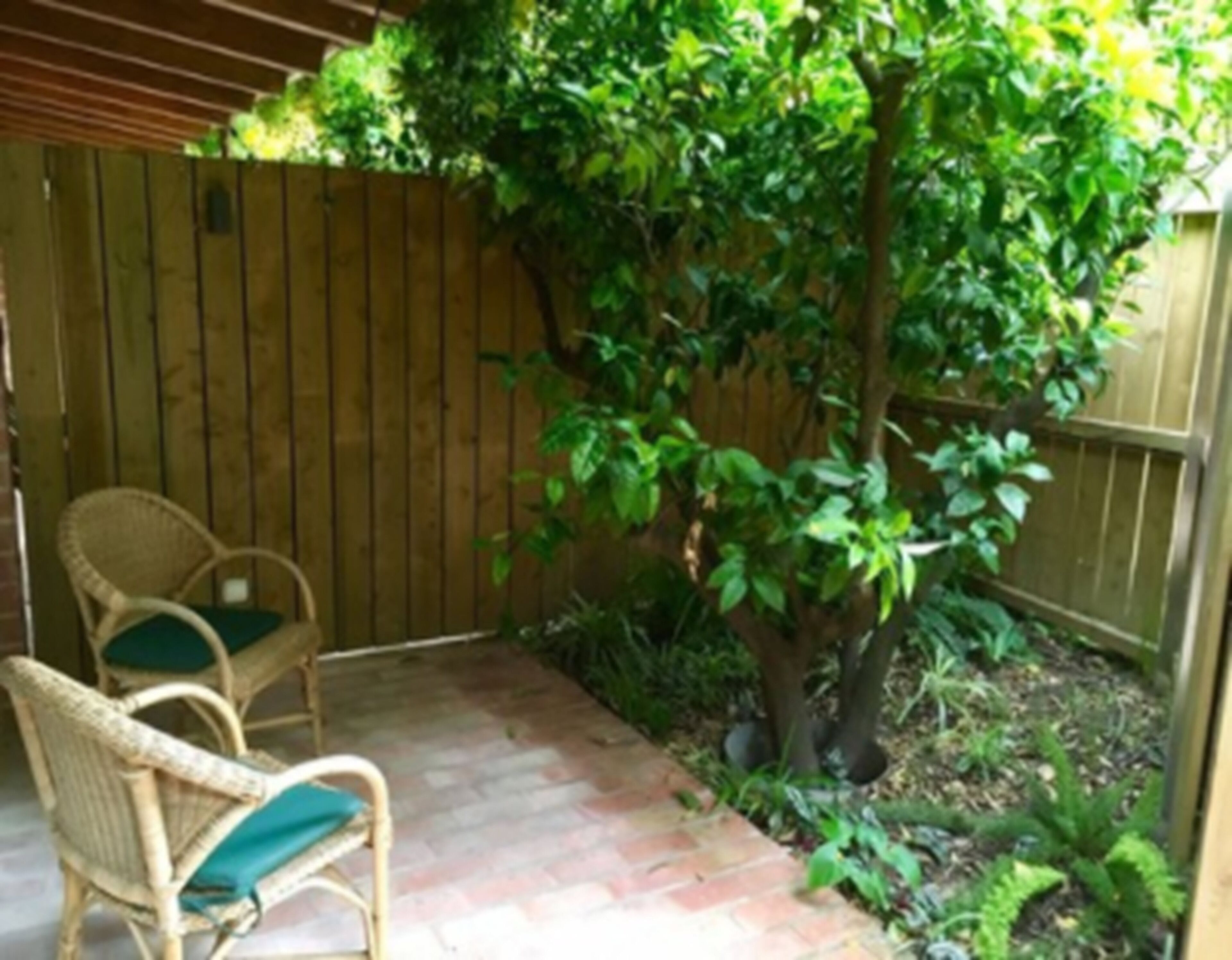 Un patio con sillas de mimbre y una valla de madera.