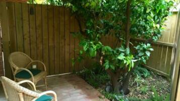 Un patio con sillas de mimbre y una valla de madera.