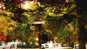 An outdoor dining area with tables and chairs, surrounded by trees. - Mont-Sant Hotel (Xàtiva)