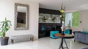 Una sala de estar moderna con un espejo grande, un banco, una mesa de comedor y un sofá.