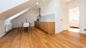 Una cocina moderna con armarios de madera, un comedor con mesa y sillas, y un tragaluz.