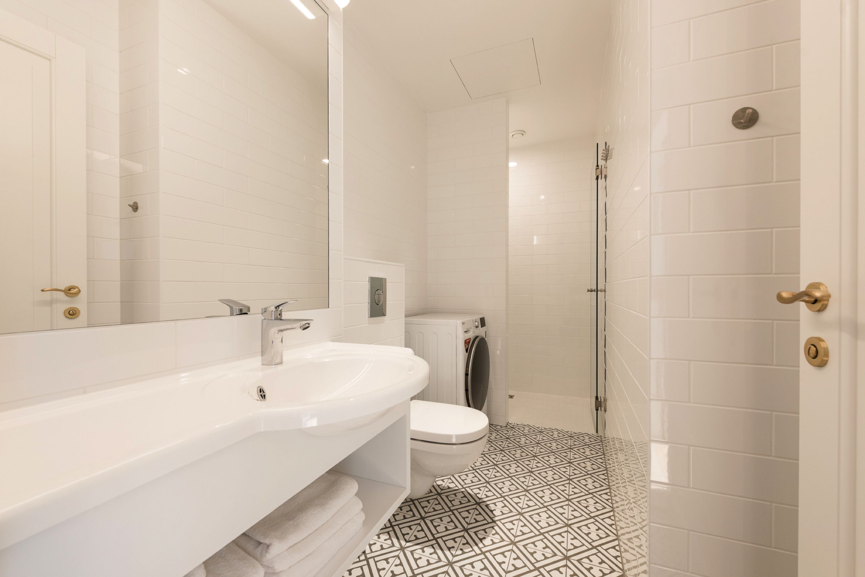 Une salle de bain moderne avec un lavabo, des toilettes et une zone de douche, le tout de couleur blanche.