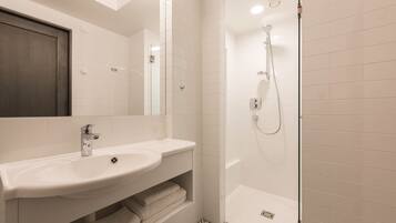 A modern bathroom with a white sink, mirror, and shower.