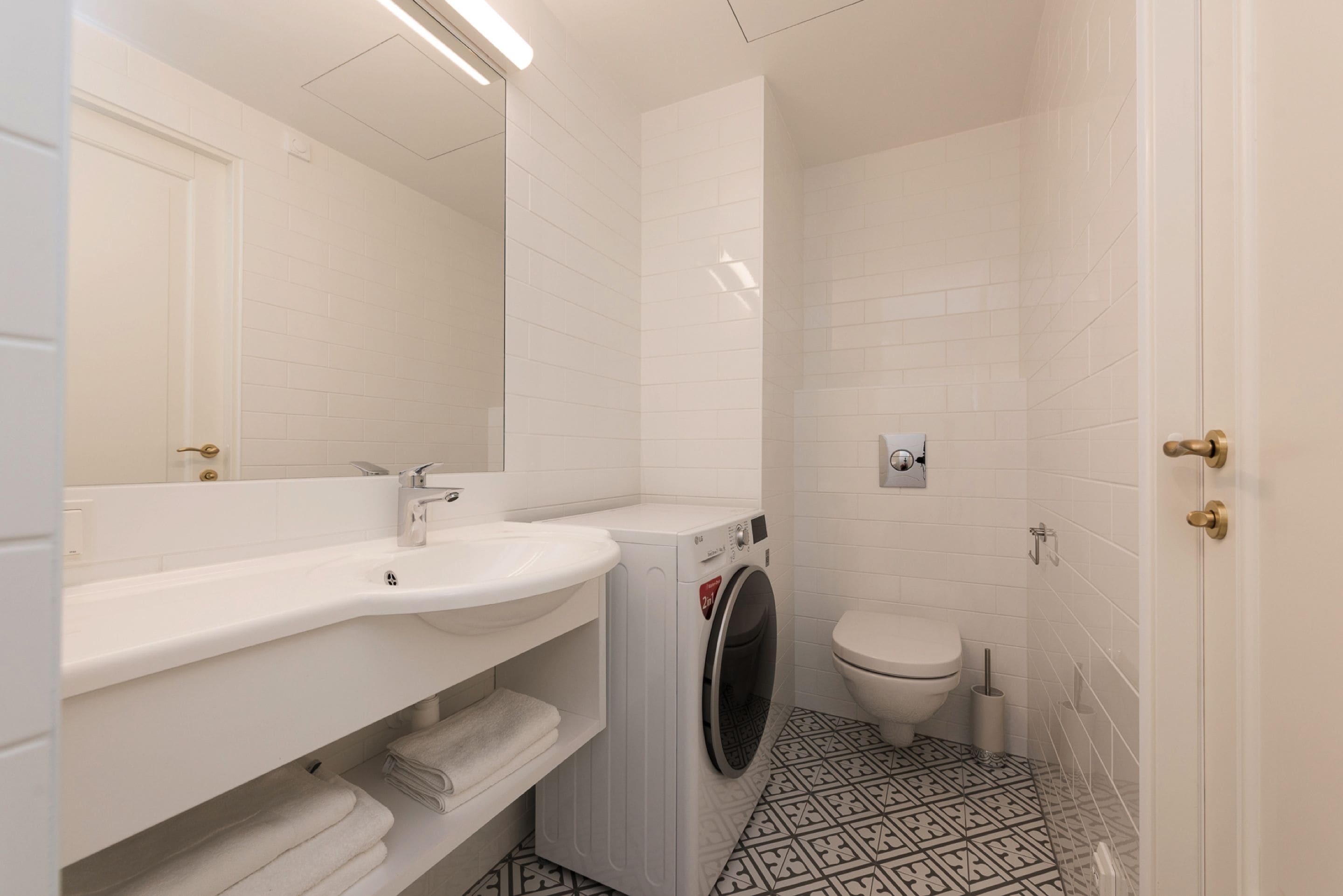 Ein kleines Badezimmer mit Waschbecken, Waschmaschine und Toilette.