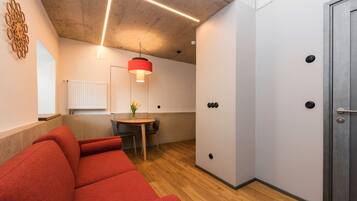 A modern room with a red sofa, a small table with a vase, and a pendant light.