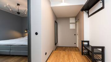 Quarto moderno com cama, corredor para um banheiro e uma pequena mesa com prateleiras.