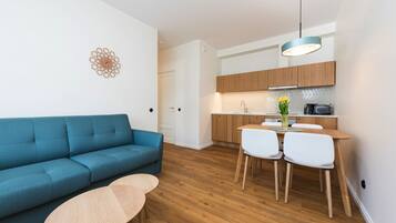 Un salon moderne avec un canapé bleu, une table basse en bois et un coin repas comprenant une table et des chaises en bois.