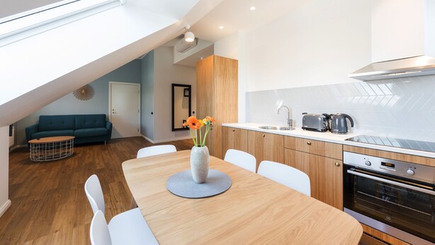 Una cocina moderna con tragaluz, armarios de madera y un comedor con mesa y sillas.