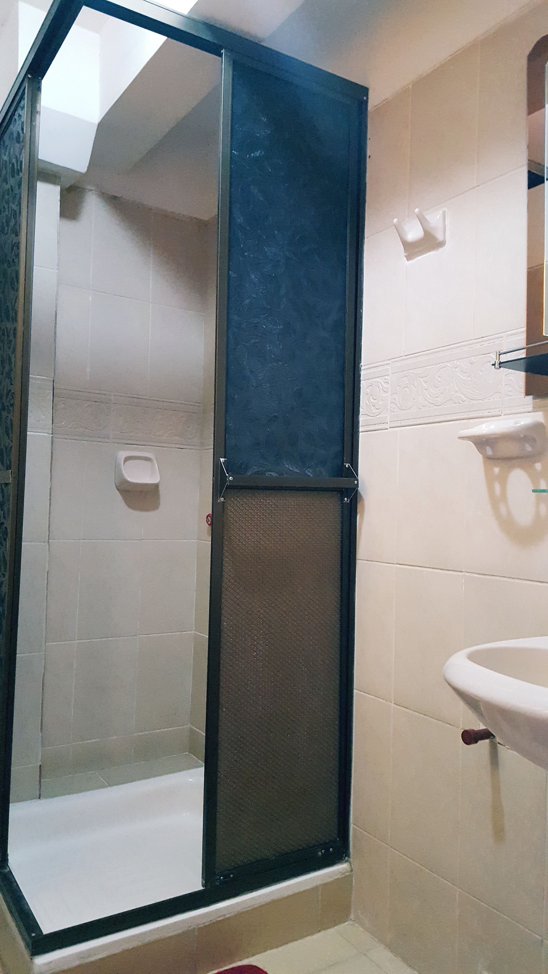 A bathroom with a shower enclosure, a sink, and a mirror.