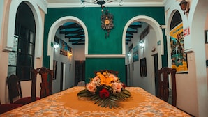 A dining area with a table set for two, flanked by wooden chairs, a green wall, and a clock above. - Hostal la Magia de Uyuni (Uyuni)