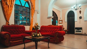 A spacious living room with two red sofas, a coffee table, and a chandelier. - Hostal la Magia de Uyuni (Uyuni)