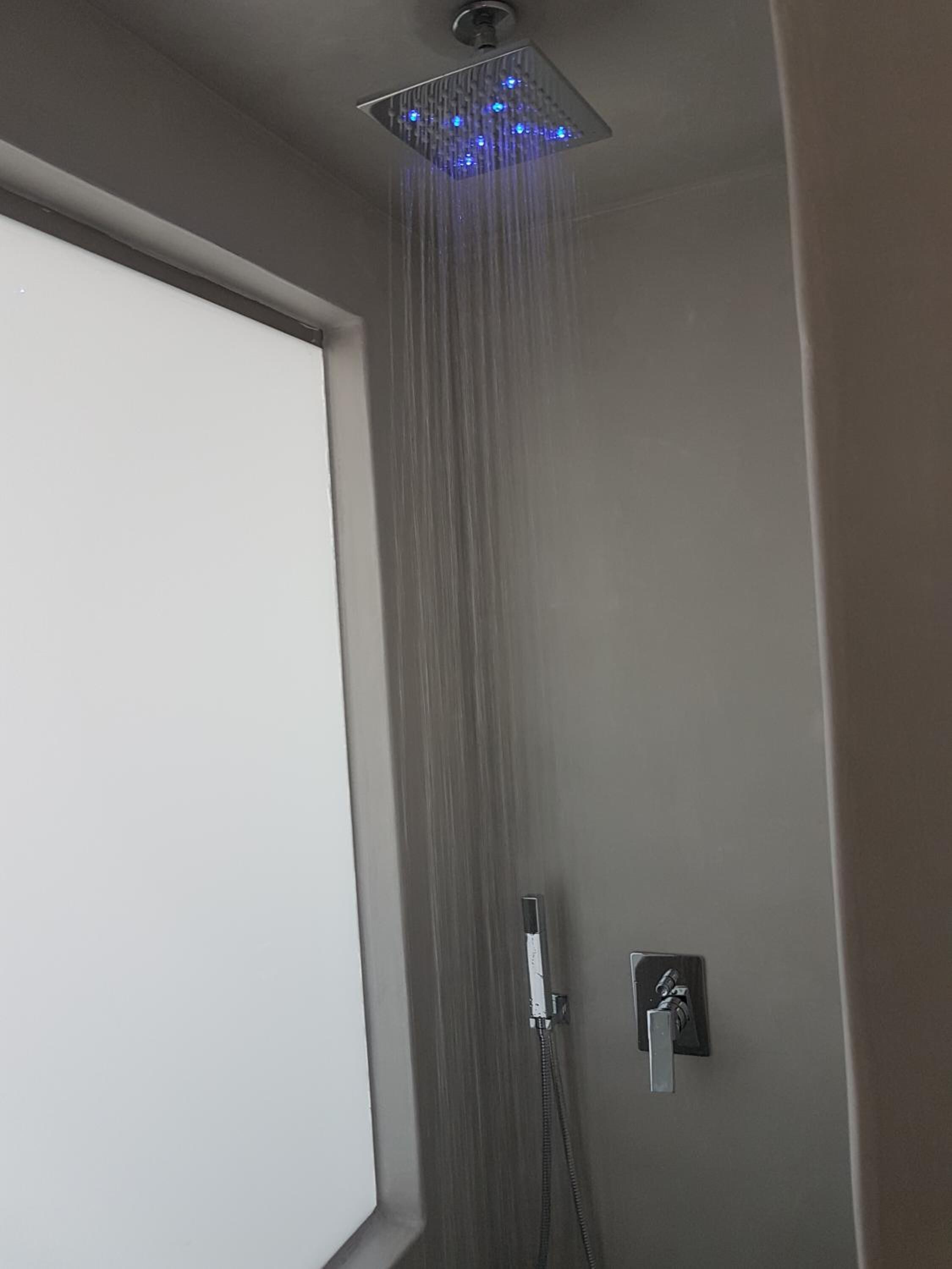 A modern shower with a square head and blue LED lights.