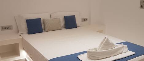 Un dormitorio moderno con una cama bien hecha, una mesita de noche y un interruptor de luz en la pared.