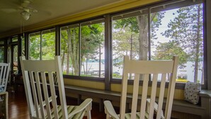 A room with large windows, white chairs with striped cushions, and a ceiling fan. - Lake Ripley Lodge w Lake Front Rooms, Grand Porch, Kayaks & Paddleboard (Cambridge)