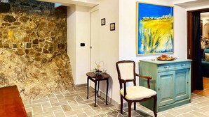 Um quarto com parede de pedra, teto de madeira, um armário azul e uma pintura.