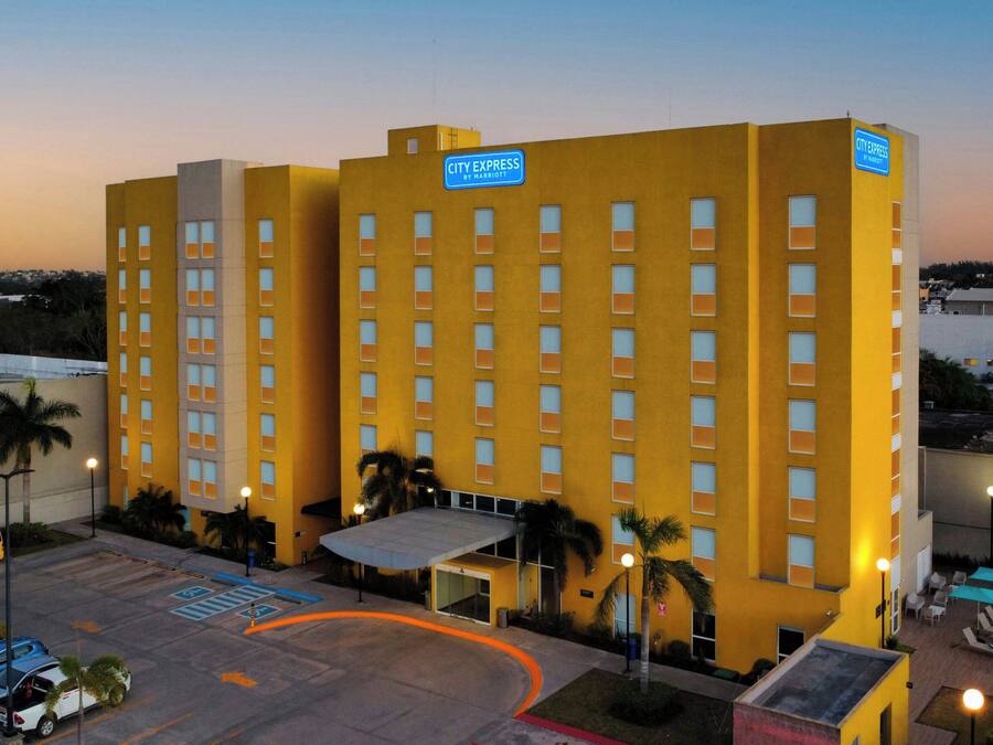 Un hotel de varios pisos con techo plano, estacionamiento y un letrero que indica que es un hotel Marriott.