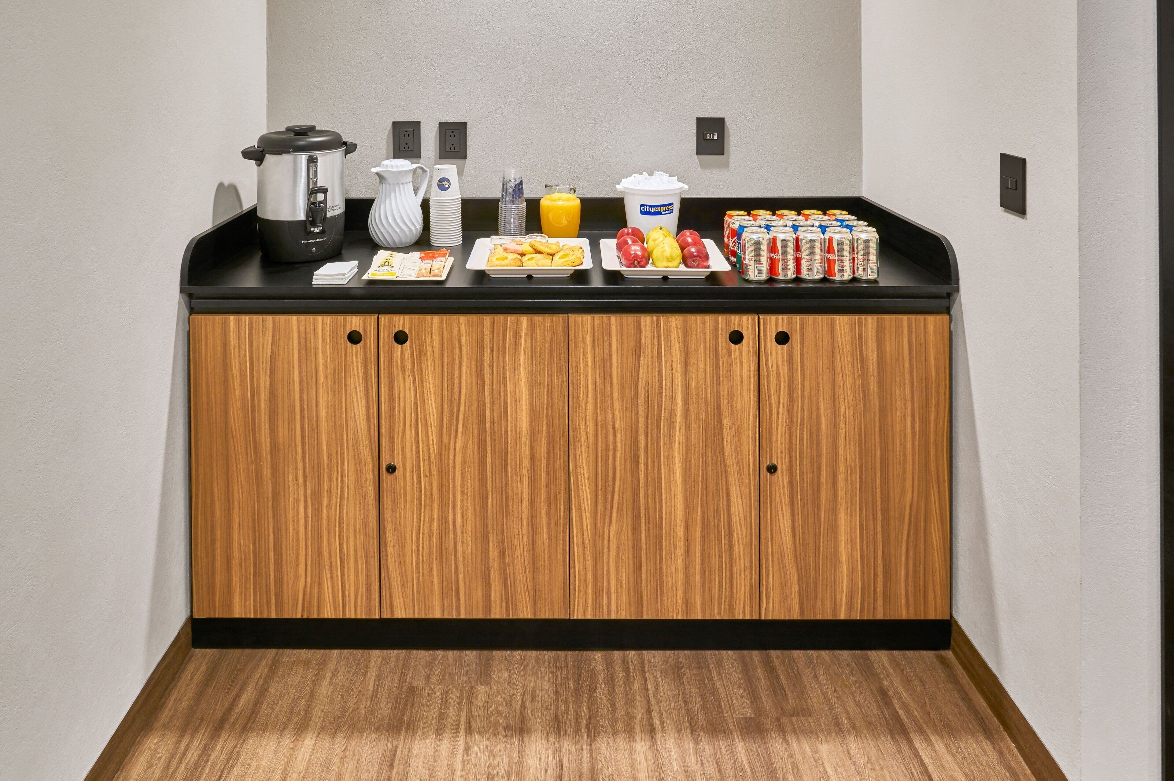 Una kitchenette equipada con cafetera, hervidor, fruta y bebidas.