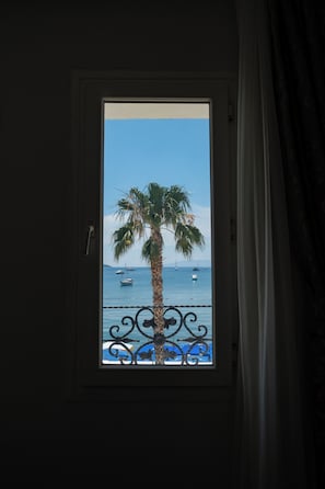 A window with a view of a palm tree and the sea. - Artemis Hotel (Bodrum)