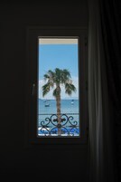 Una ventana con vista a una palmera y al mar.