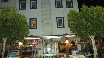 Un edificio con un cartel que dice "DING" y un restaurante con terraza.