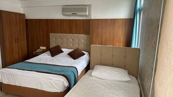 Habitación de hotel con dos camas, un armario, un teléfono y una ventana con cortinas.