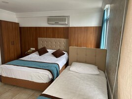 Habitación de hotel con dos camas, un armario, un teléfono y una ventana con cortinas.