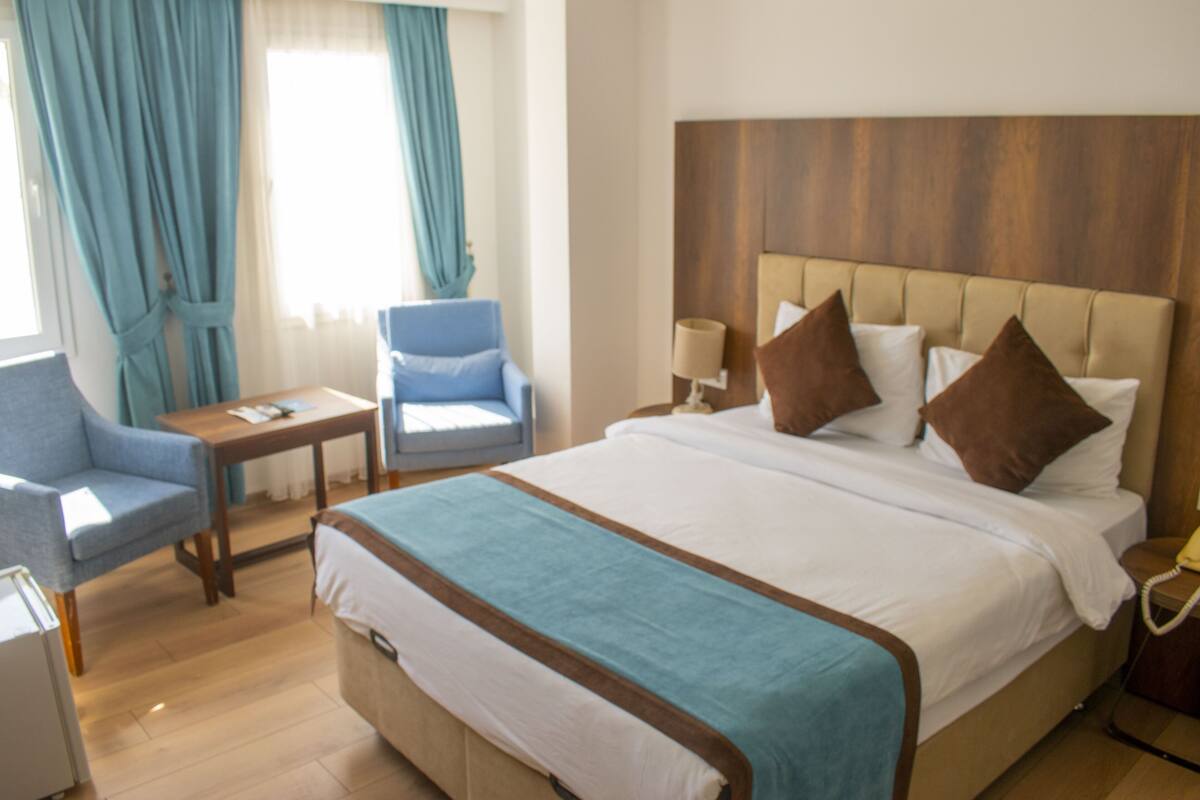 Ein Hotelzimmer mit einem großen Bett, einem Nachttisch, einem Sessel und einer Lampe.