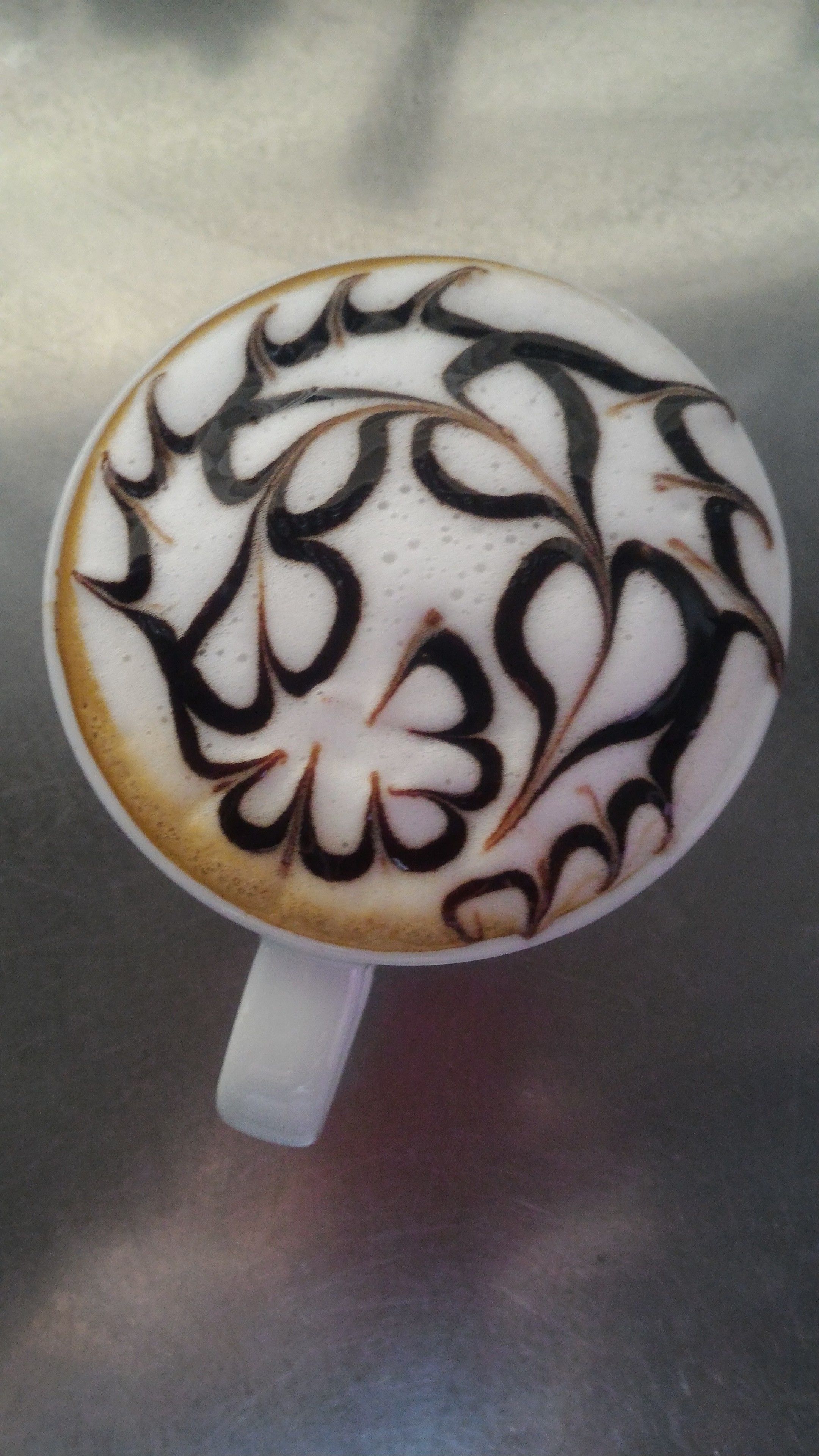 Une tasse de café agrémentée d’un motif complexe réalisé avec de la mousse de lait.