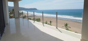 A balcony with a view of a beach and ocean.