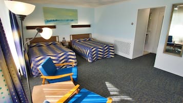 A hotel room with two beds, a desk, a chair, a lamp, and a painting on the wall.