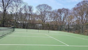 A tennis court with a net, surrounded by trees and a fence. - Harborside Motel (Montauk)
