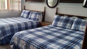 A room with two beds, each with a blue and white checkered bedspread, a wooden headboard, a bedside table, and a mirror on the wall. - Harborside Motel (Montauk)