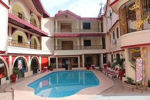 Une cour d’hôtel dotée d’une piscine, de nombreux balcons et d’espaces aménagés pour se détendre en plein air.