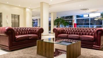 A lobby with two red leather sofas and a glass coffee table.