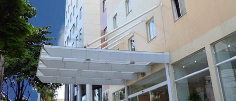 Un hotel de varios pisos con un diseño moderno, que presenta una zona de entrada techada y grandes ventanales.