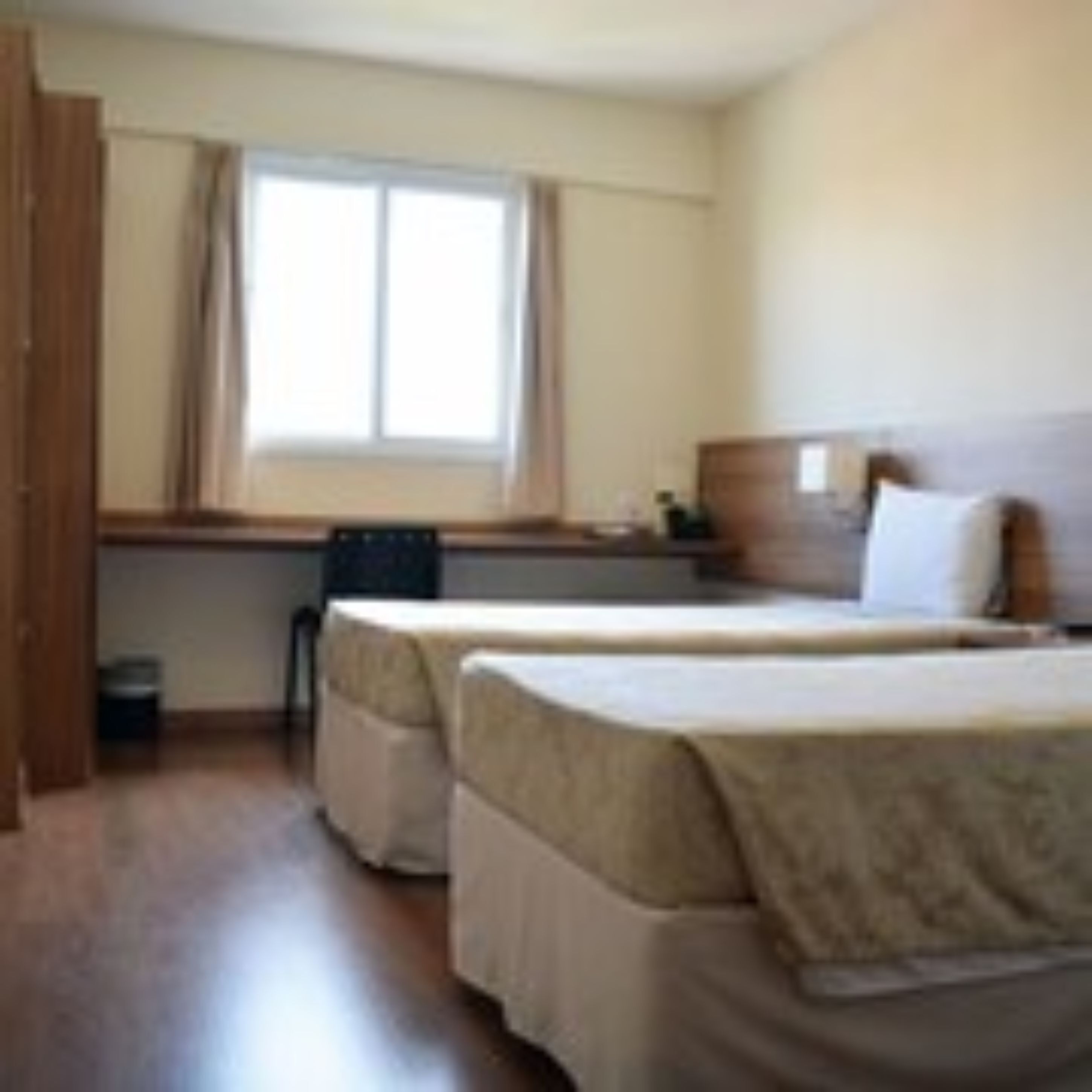 Habitación de hotel con dos camas, un escritorio y una ventana.