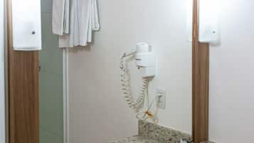 Baño con encimera de granito, lavamanos, espejo y toallero con toallas.