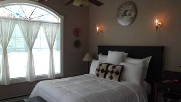 Quarto com cama, ventoinha no teto, relógio e janela com cortinas.