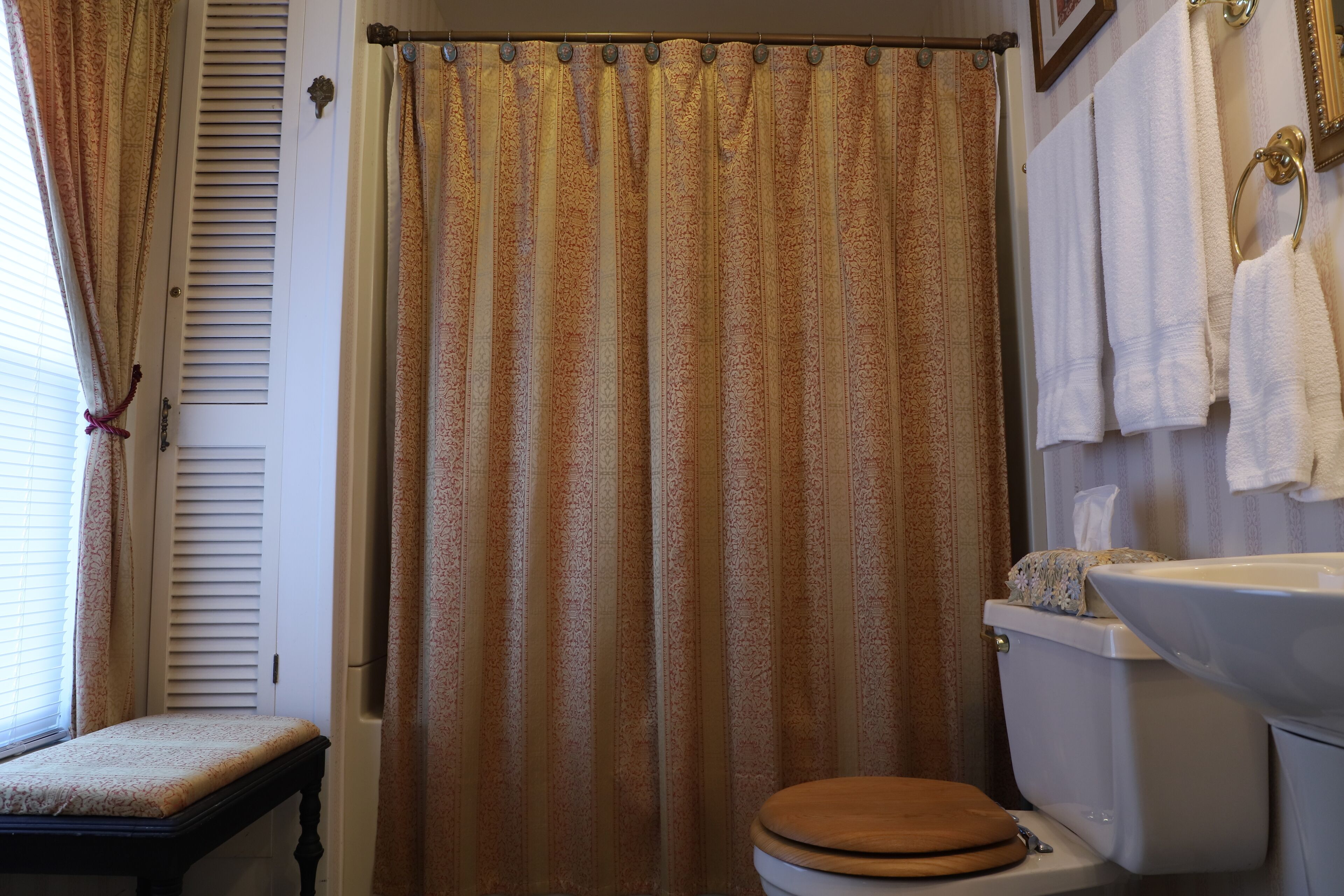 Un baño con cortina de ducha, un inodoro, un lavabo y toallas colgadas en la pared.