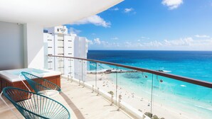 A balcony with a view of a beach and ocean, a hot tub, and a seating area with chairs. - Altitude at Krystal Grand Cancun - All inclusive (Cancun)