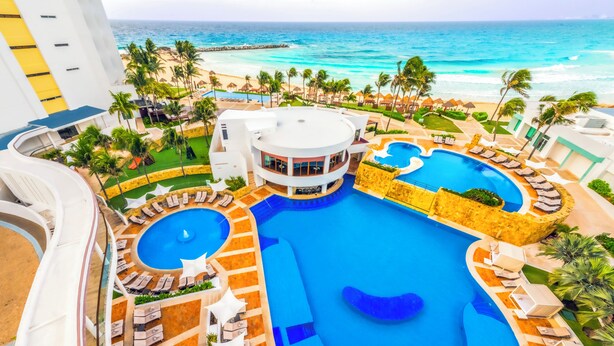 A resort with a large central pool, multiple smaller pools, and a beach area with palm trees. - Altitude at Krystal Grand Cancun - All inclusive (Cancun)